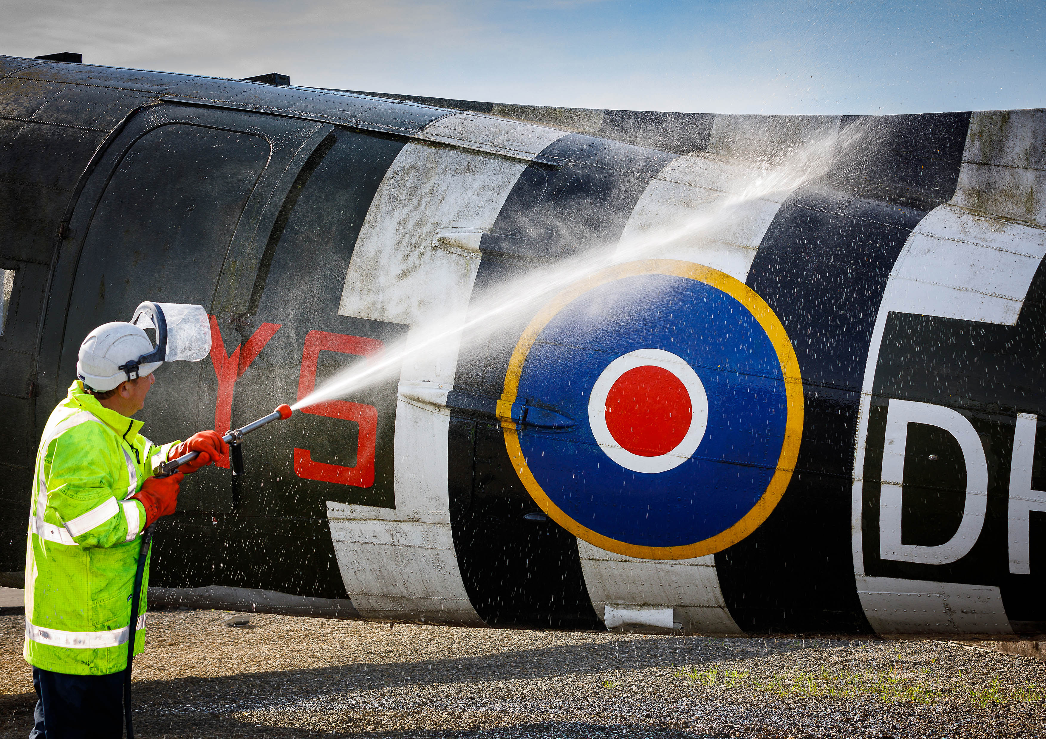 Photo: A member of the Serco Aircraft Wash Team pressure washing the aircraft structure aft of the cargo door